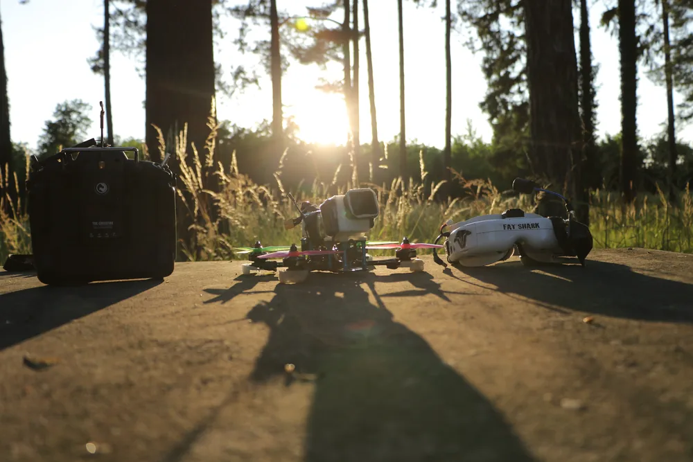 Aparatura RC, quad FPV i gogle Fat Shark na drewnianym blacie w lesie