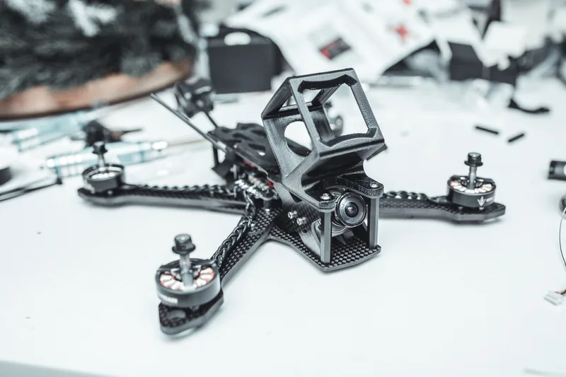 Karbonowy quad FPV bez śmigieł na stole warsztatowym